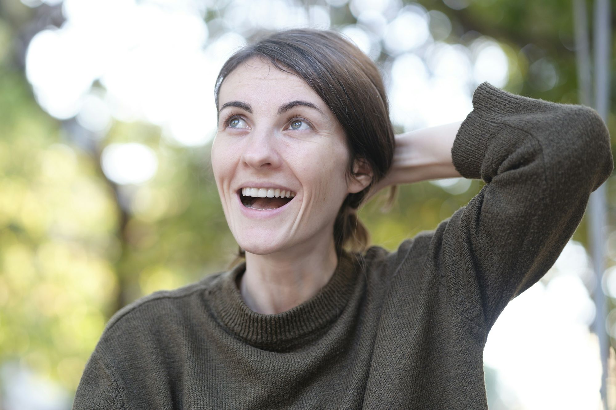A woman laughing outdoors in autumn light